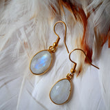 Boucles d'oreilles KAUMUDI Ginandger sur plumes blanches – détail des pierres de lune facettées à reflets bleus et crochet doré, boucles pendantes pierres naturelles Ginandger
