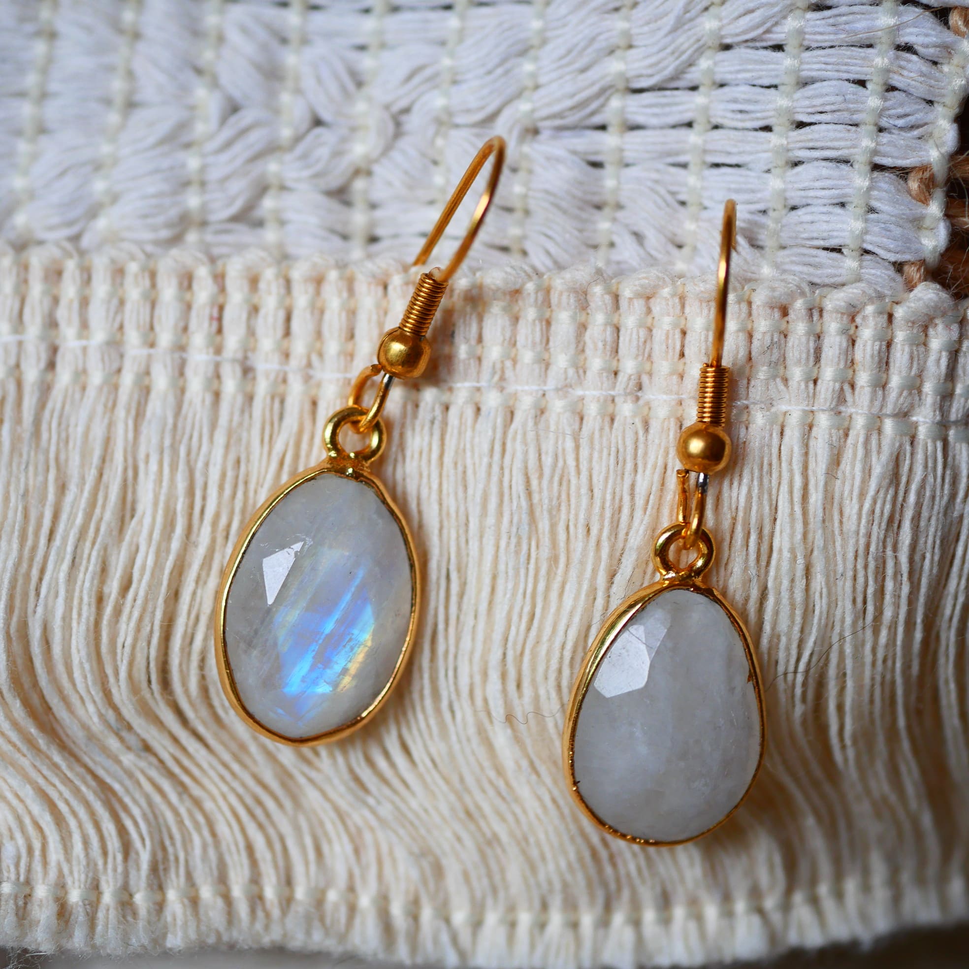 Boucles d'oreilles KAUMUDI Ginandger portées au soleil – pierre de lune ovale sertie or à reflets irisés, look été bijoux pierres naturelles
