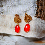 Boucles d'oreilles VEGA Ginandger sur fond macramé – cornalines rouge-orangé facettées et puces feuille dorées, boucles pendantes pierres naturelles Ginandger
