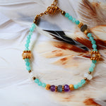 Bracelet LAKSHYA Ginandger posé sur plumes blanches – amazonites, améthystes, citrines et labradorites, perles dorées ciselées, bijou pierres naturelles fait main à Paris
