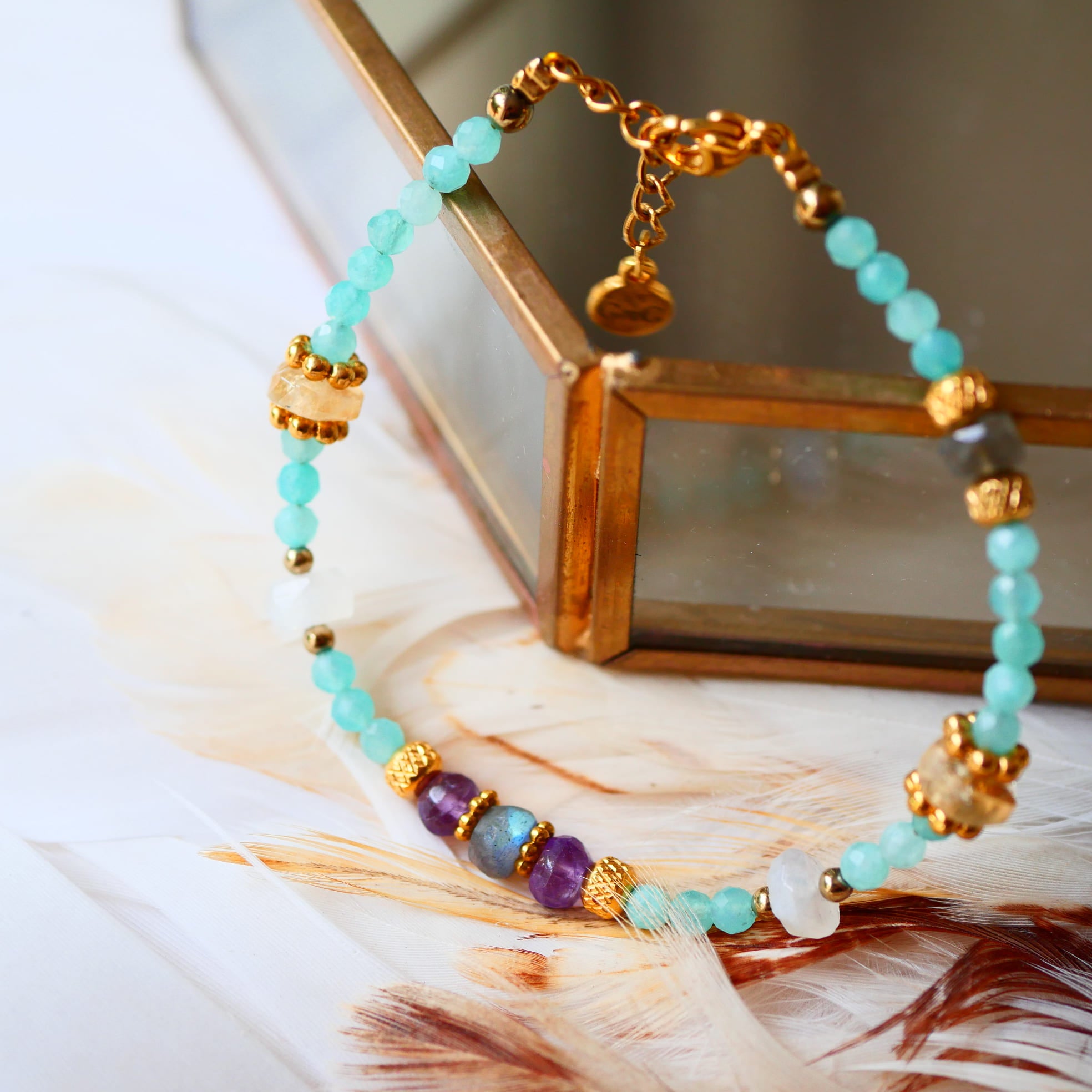 Bracelet LAKSHYA Ginandger sur plumes et miroir doré – détail des amazonites bleu-vert, améthystes et citrines facettées, perles dorées, bracelet pierres naturelles Ginandger
