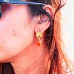 Boucles d'oreilles VEGA Ginandger portées au soleil – cornaline rouge-orangé facettée et puce feuille dorée texturée, look été bijoux pierres naturelles
