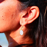 Boucles d'oreilles KAUMUDI Ginandger sur macramé blanc – pierres de lune ovales irisées serties or, crochet doré, boucles artisanales pierres naturelles Paris

