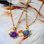 Collier AJNA Ginandger - pendentif œil améthyste violet et labradorite bleue sur chaîne dorée, fond plumes
