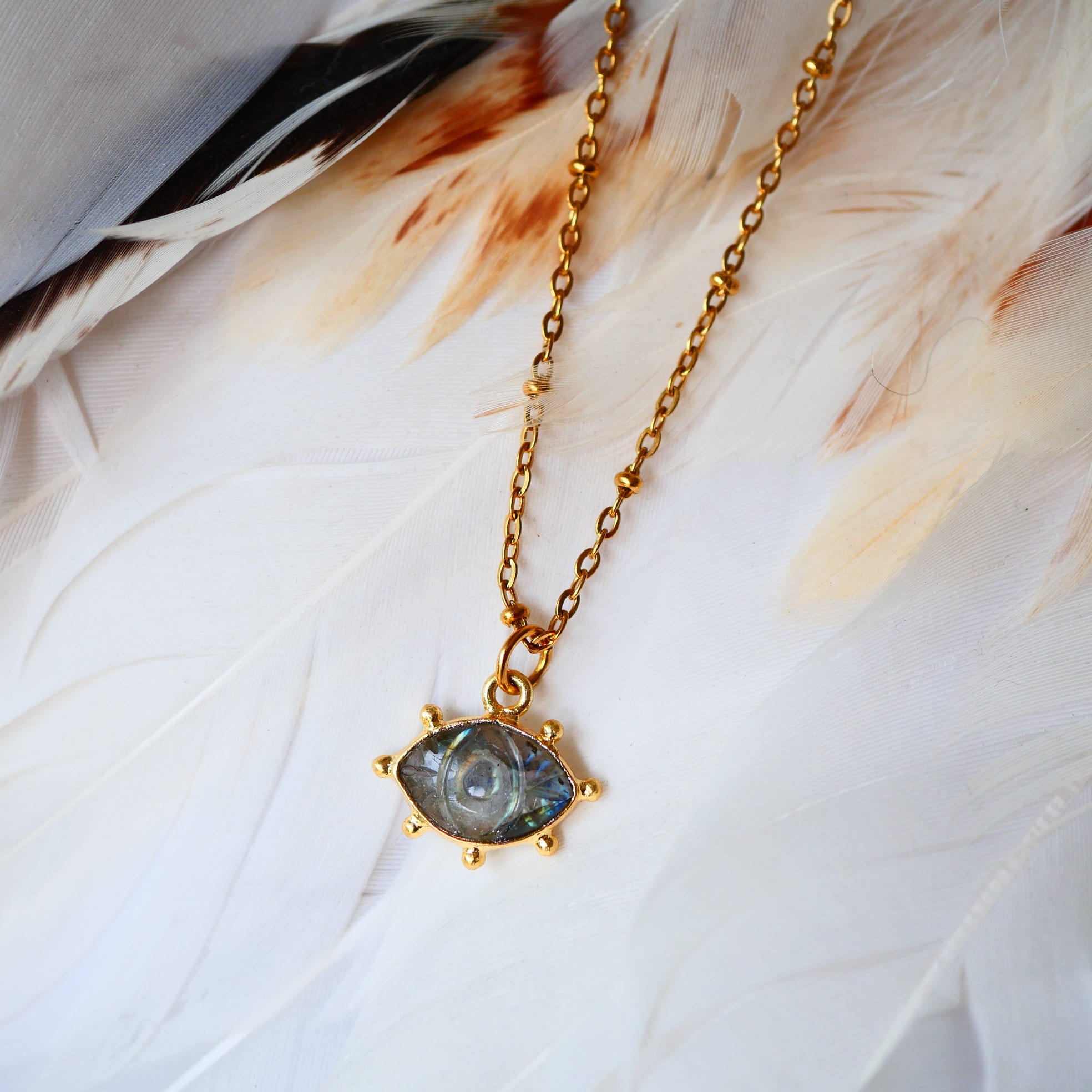 Collier AJNA Ginandger labradorite - pendentif œil sculpté bleu irisé serti or, fond plumes blanches
